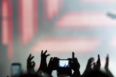 People taking photographs with touch smart phone during a music entertainment public concert 