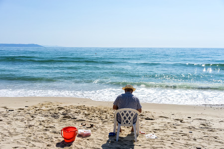 Back view of senior looking over the sea on the beachの写真素材