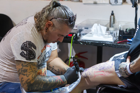 THESSALONIKI, GREECE- SEPTEMBER 19, 2014: Tattoo artist works in The 1st Thessalonink International Tattoo Convention, in Greece. Convention was held in Thessaloniki Port Warehouse C.のeditorial素材
