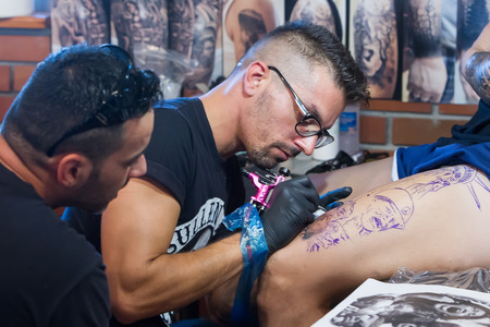 THESSALONIKI, GREECE- SEPTEMBER 19, 2014: Tattoo artist works in The 1st Thessalonink International Tattoo Convention, in Greece. Convention was held in Thessaloniki Port Warehouse C.のeditorial素材