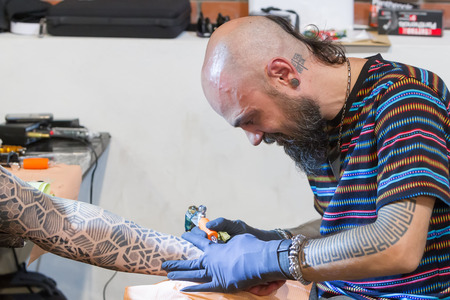 THESSALONIKI, GREECE- SEPTEMBER 19, 2014: Tattoo artist works in The 1st Thessalonink International Tattoo Convention, in Greece. Convention was held in Thessaloniki Port Warehouse C.のeditorial素材