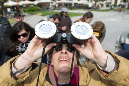 THESSALONIKI, GREECE, MARCH 20, 2015: People use binoculars with special filters to look into the sky at a partial solar eclipse. Over Greece the moon was scheduled to cover approximately 45%.のeditorial素材