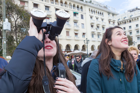 THESSALONIKI, GREECE, MARCH 20, 2015: People use binoculars with special filters to look into the sky at a partial solar eclipse. Over Greece the moon was scheduled to cover approximately 45%.のeditorial素材