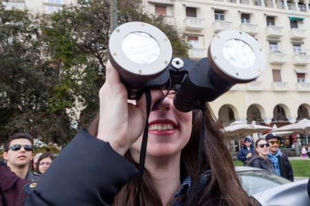 THESSALONIKI, GREECE, MARCH 20, 2015: People use binoculars with special filters to look into the sky at a partial solar eclipse. Over Greece the moon was scheduled to cover approximately 45%.のeditorial素材