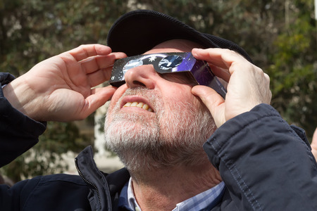 THESSALONIKI, GREECE, MARCH 20, 2015: People use special glasses to look into the sky at a partial...