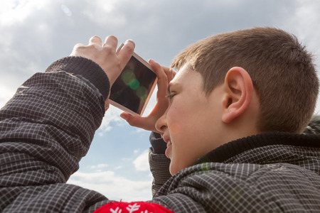 THESSALONIKI, GREECE, MARCH 20, 2015: People use special filters to look into the sky at a partial solar eclipse. Over Greece the moon was scheduled to cover approximately 45%のeditorial素材