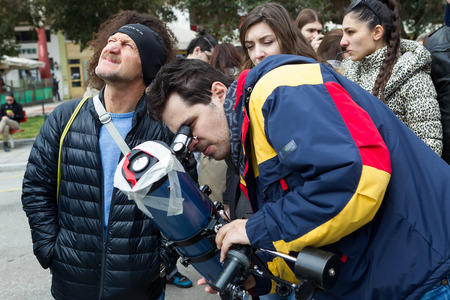 THESSALONIKI, GREECE, MARCH 20, 2015: People watch through a telescope into the sky at a partial...