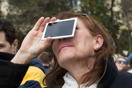 THESSALONIKI, GREECE, MARCH 20, 2015: People use special filters to look into the sky at a partial solar eclipse. Over Greece the moon was scheduled to cover approximately 45%のeditorial素材