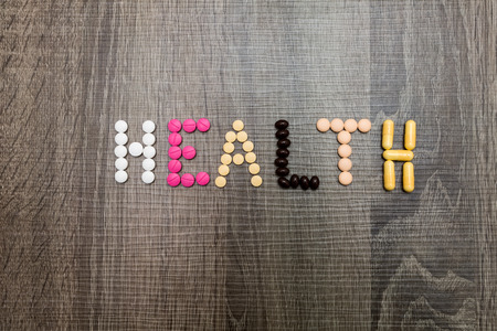 The word health written whith pills on a wooden background.の写真素材