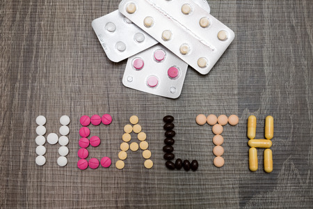 The word health written whith pills on a wooden background.の写真素材