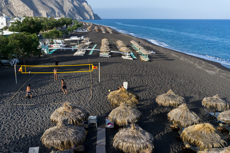 SANTORINI, GREECE - MAY 15,2015: Top view of Perissa beach on the Greek island of Santorini with sunbeds and umbrellas. Beach is covered with fine black sand, and drops off sharply into the water.のeditorial素材