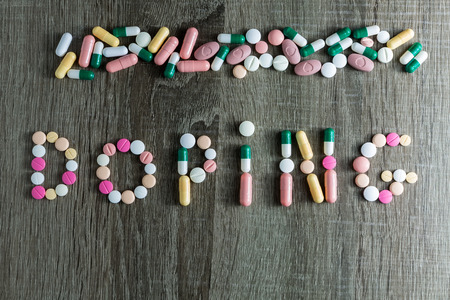 The word doping written with pills on a wooden background.の写真素材