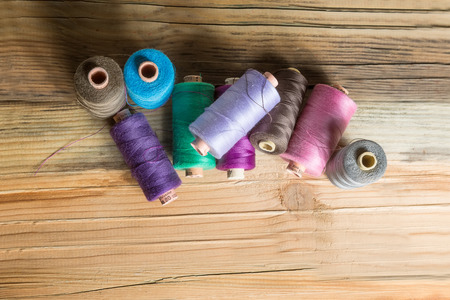 Spools of thread on wooden  background. Old sewing accessories. colored threads