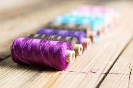 Spools of thread on wooden  background. Old sewing accessories. colored threads