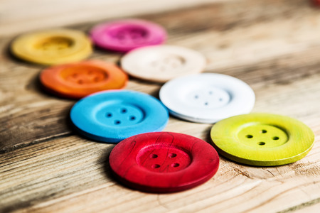 colored buttons on wooden board, Colorful buttons, on old wooden texture backgroundの写真素材
