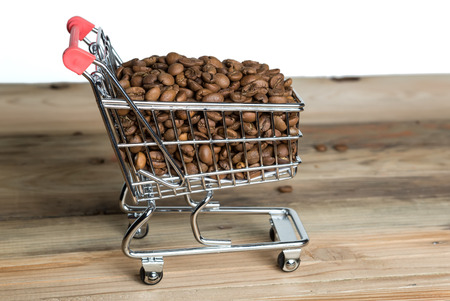 The shopping cart with coffee beans on wooden tableの写真素材