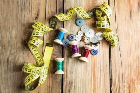 Spools of thread with needles on wooden background. Old sewing accessories. colored threadsの写真素材