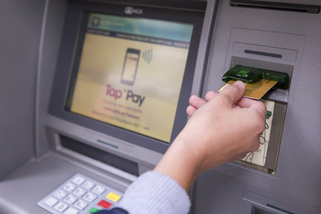 THESSALONIKI, GREECE,JUN 27 2015: People stand in a queue to use the ATMs of a bank. Person receiving money from the ATM.のeditorial素材