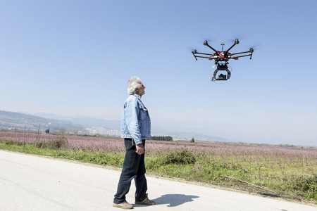 Athens, Greece, March 30, 2015: Man watches DJI S900 drone in flight with a mounted sony A7 Edition...