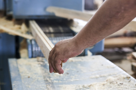 Thessaloniki, Greece, July 8, 2015: Craftsmen cut a piece of wood at a woodworking factory in Greece. Wood and furniture production plant, industrial factory with tools and objects.のeditorial素材