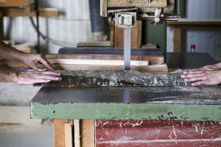 Thessaloniki, Greece, July 8, 2015: Craftsmen cut a piece of wood at a woodworking factory in Greece. Wood and furniture production plant, industrial factory with tools and objects.のeditorial素材
