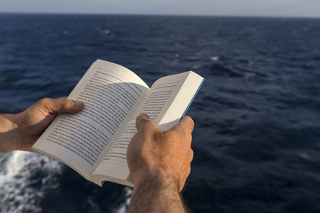 Hands with a book on the deck of a ship.の写真素材