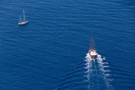 Santorini, Grece- May 13, 2015: Yacht navigates into beautiful blue water near Santorini island, Aegean sea in Greece.のeditorial素材
