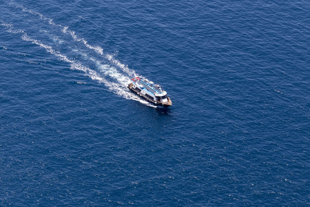 Yacht navigates into beautiful blue water near Santorini island, Aegean sea in Greece.