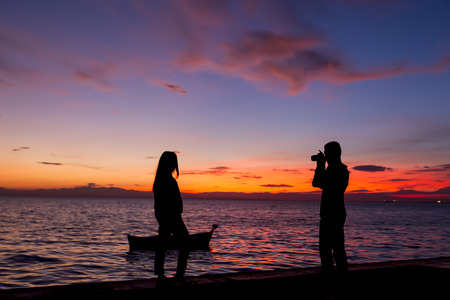 The Silhouettes are doing Activities on the Beach at Sunsetの写真素材