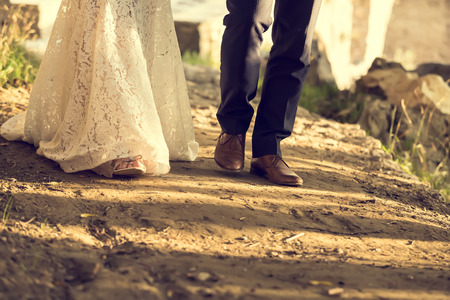 feet of bride and groom walking, wedding shoes (soft focus). Cross processed image for vintage lookの写真素材