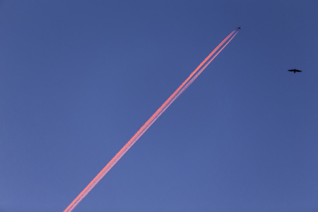 Airplane with contrail high in the sky at sunset