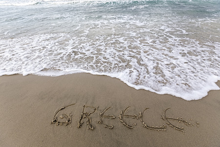 Greece writing on the sand with water coming to erase itの写真素材