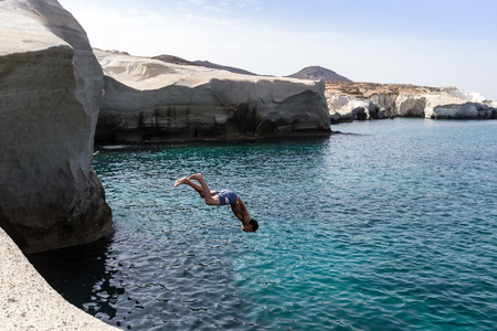 Milos, Greece - September 9, 2015: Tourists jump in the clear water of Sarakiniko beach in Milos,...