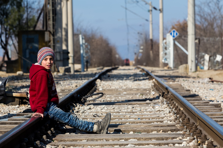 Idomeni, Greece, February 7, 2016:A refugee child sits on the railway near the border crossing between Greece and FYROM as waiting to cross the border to FYR of Macedoniaのeditorial素材