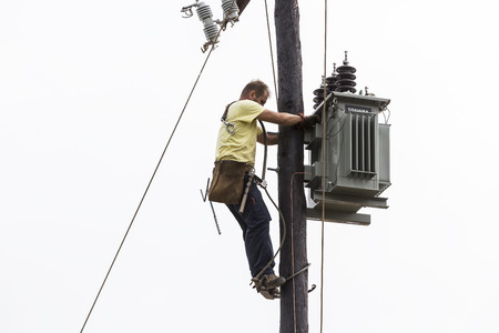 Thessaloniki, Greece- September 24, 2015: Worker climbing on Electrical concrete pole transmission line tower in Thessaloniki, Greece.のeditorial素材