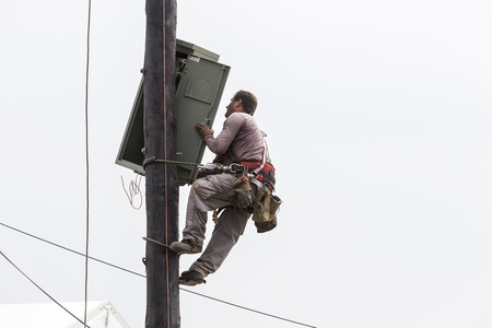 Thessaloniki, Greece- September 24, 2015: Worker climbing on Electrical concrete pole transmission line tower in Thessaloniki, Greece.のeditorial素材