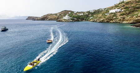 Ios, Greece - September 19, 2015: Tourists having fun on inflatable watercraft boat at the beautiful ocean of Greek island of Ios island, Cyclades, Greece.のeditorial素材