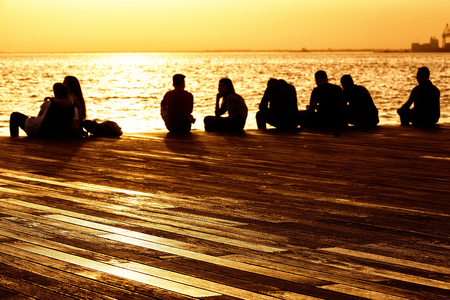 people relax on the waterfront at sunsetの写真素材