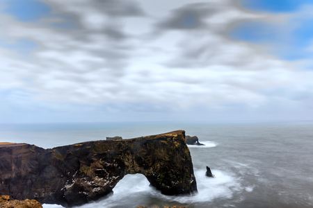 Magnificent rock arch at Dyrholaey, Iceland. Dyrholaey means the hill island with the door hole. It...