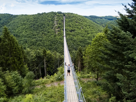 Geierlay, Morsdorf, Germany - July 11, 2017: Holidaymakers cross Germany's longest rope suspension...