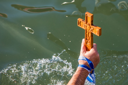 Thessaloniki, January 6, 2018: close-up shot of the hand that retrieves a wooden cross in the sea,...