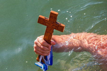 Thessaloniki, January 6, 2018: close-up shot of the hand that retrieves a wooden cross in the sea, at the blessing of the water ceremony marking the Orthodox Epiphany, at the harbor of Thessalonikiのeditorial素材
