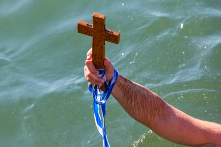 Thessaloniki, January 6, 2018: close-up shot of the hand that retrieves a wooden cross in the sea,...