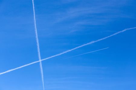 Long white trail in beautiful blue sky from engine flying plane の写真素材