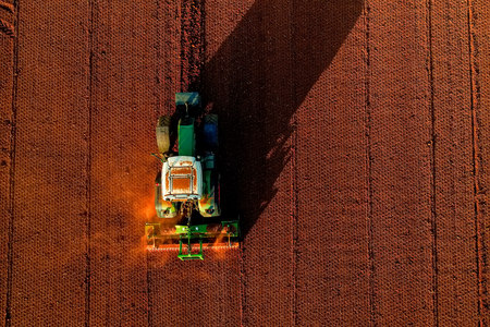 Aerial shot of  Farmer with a tractor on the agricultural field sowing. tractors working on the agricultural field in spring. Cotton seedの写真素材