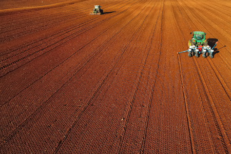 Aerial shot of  Farmer with a tractor on the agricultural field sowing. tractors working on the agricultural field in spring. Cotton seedの写真素材