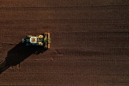 Aerial shot of  Farmer with a tractor on the agricultural field sowing. tractors working on the agricultural field in spring. Cotton seedのeditorial素材