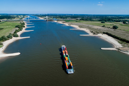 Rhine - Netherlands, July 14, 2018: aerial view of a merchant ship with a container crossing the river Rhine in a region of the Netherlandsのeditorial素材