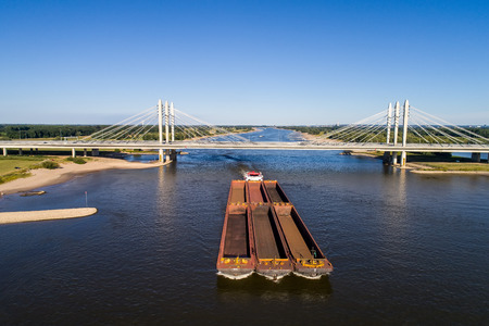 Aerial view of the ship crossing under a bridge on the river Rhine in an area of the Netherlands