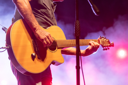 Thessaloniki, Greece - September 22, 2018: acoustic guitar in action on stage performing at a rock concert at the open theater of the city, blur stage spotlight with laser rays.のeditorial素材